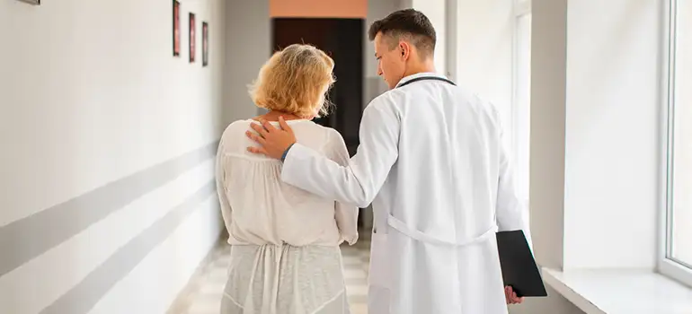 doctor tocando la espalda de un paciente después de un diagnóstico grave
